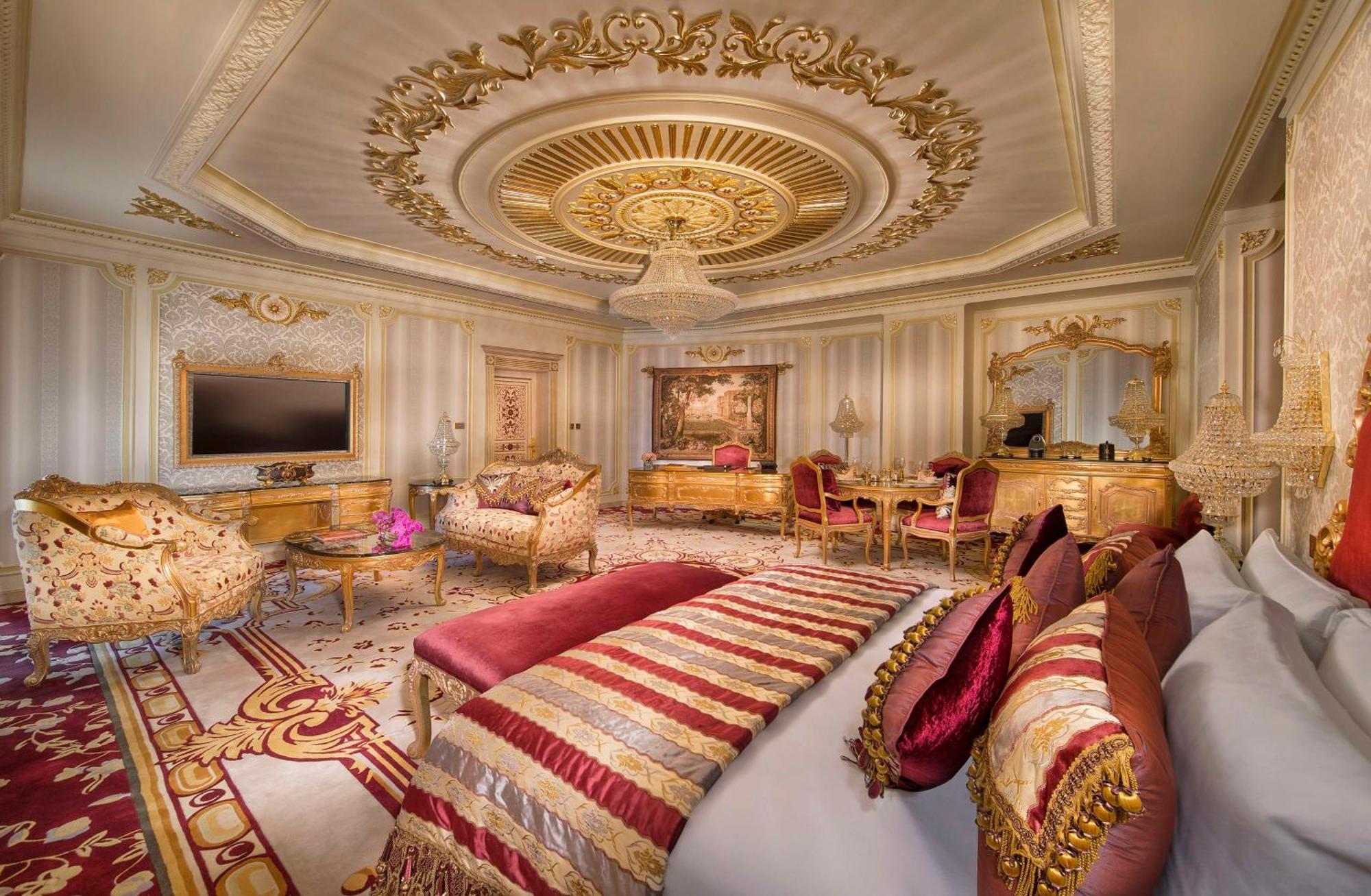 Royal Rose Abu Dhabi, A Curio Collection By Hilton Affiliated Hotel Exterior photo The photo shows an opulent hotel room featuring luxurious decor. The ceiling is intricately designed with ornate details and a central chandelier, adding to the elegance of the space. The room includes a plush bed adorned with decorative pillows in r
