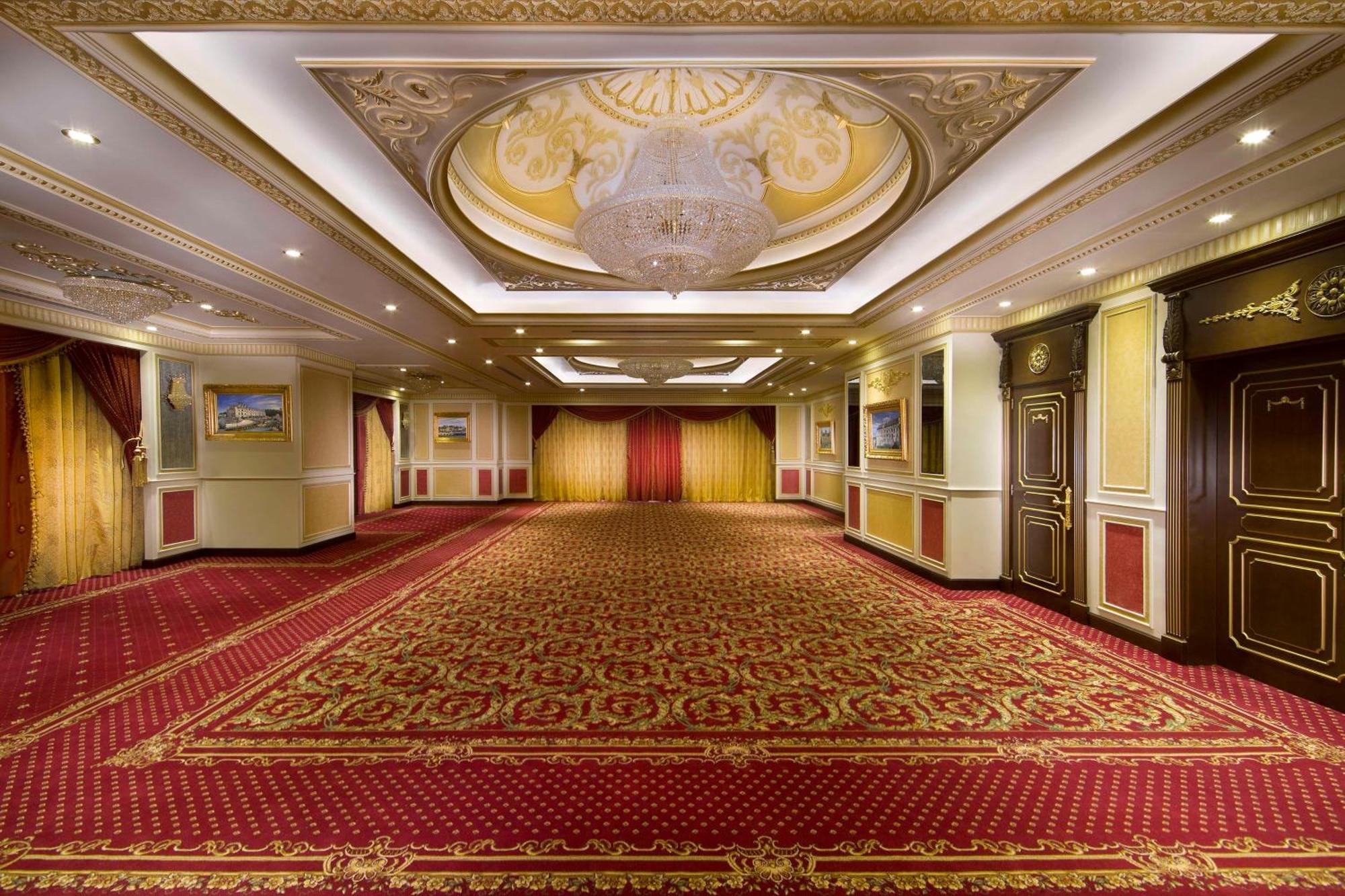 Royal Rose Abu Dhabi, A Curio Collection By Hilton Affiliated Hotel Exterior photo The photo shows the interior of a spacious, elegantly designed room. The ceiling features intricate detailing with a large chandelier at the center, providing a luxurious touch. The walls are adorned with decorative moldings and panels, while the car