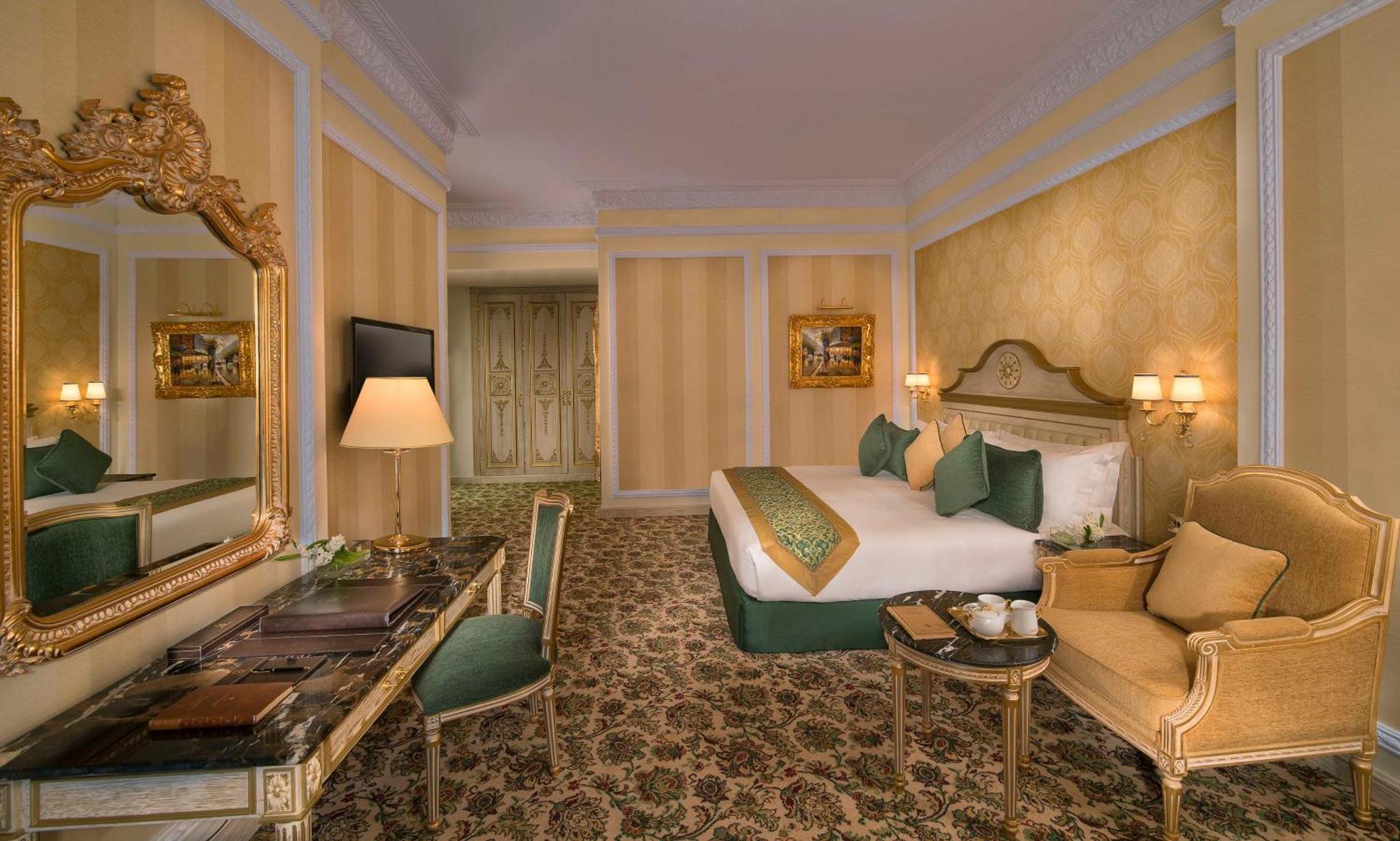 Royal Rose Abu Dhabi, A Curio Collection By Hilton Affiliated Hotel Exterior photo The photo depicts an elegantly designed hotel room. It features a large bed with green and white accents, topped with decorative pillows. A plush chair and a small table are positioned next to the bed, complemented by a stylish desk and a mirror. The