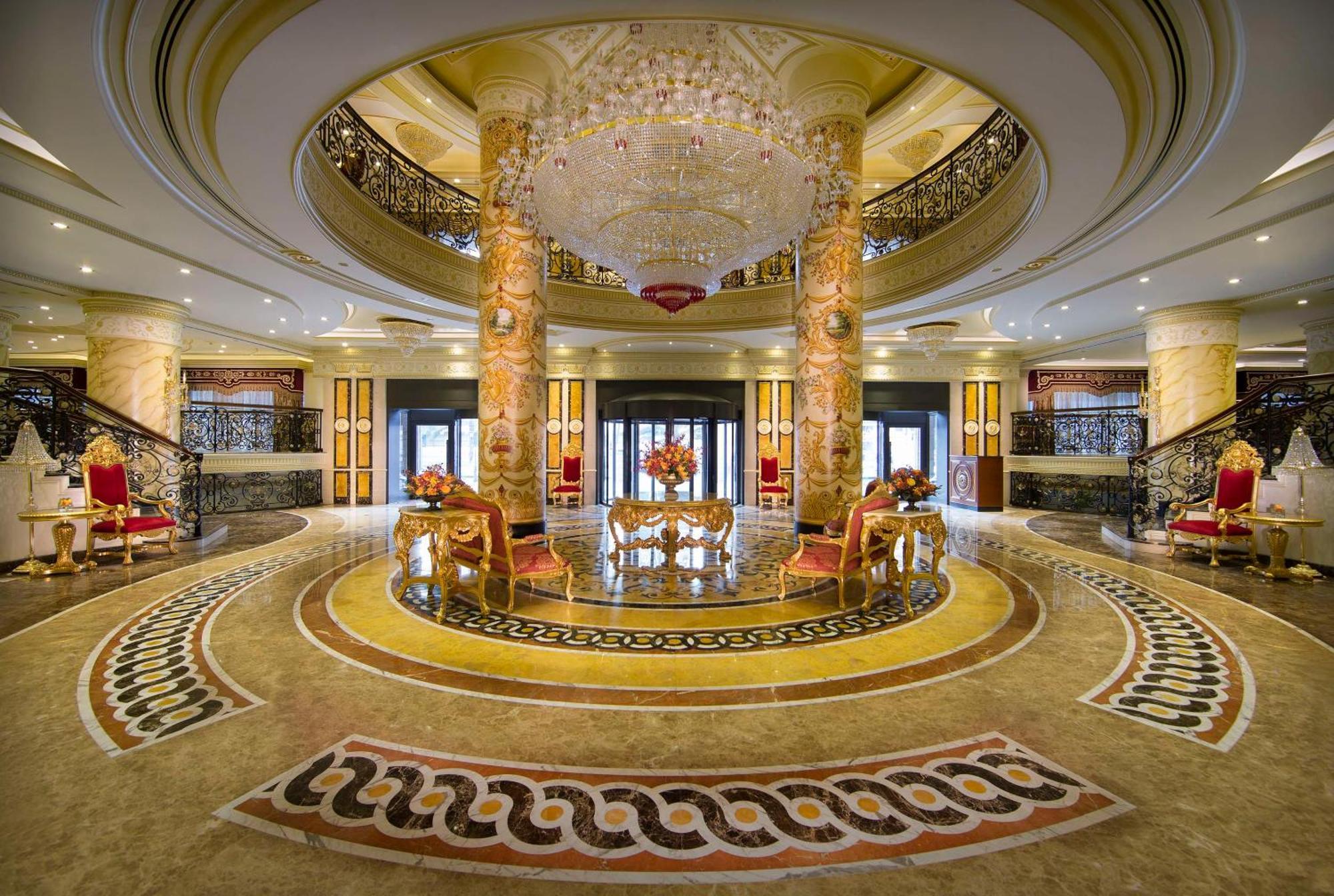 Royal Rose Abu Dhabi, A Curio Collection By Hilton Affiliated Hotel Exterior photo The photo shows an elegant hotel lobby featuring ornate architectural details. There are tall, decorative columns with intricate designs and a grand chandelier hanging from the ceiling, adding a luxurious touch. The flooring is beautifully patterned,