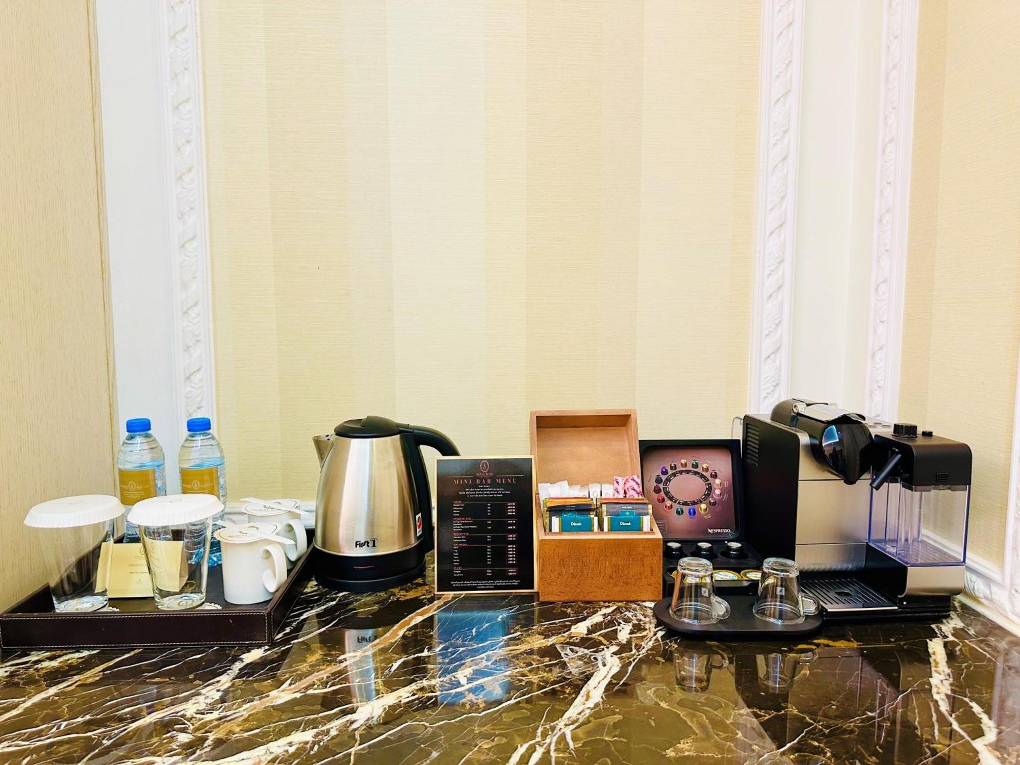 Royal Rose Abu Dhabi, A Curio Collection By Hilton Affiliated Hotel Exterior photo The photo shows a hotel or room beverage station on a marble countertop. It includes:

- Two bottles of water.
- A kettle for boiling water.
- Two cups and a small container, likely for sugar or cream.
- A menu or information card detailing drink opt