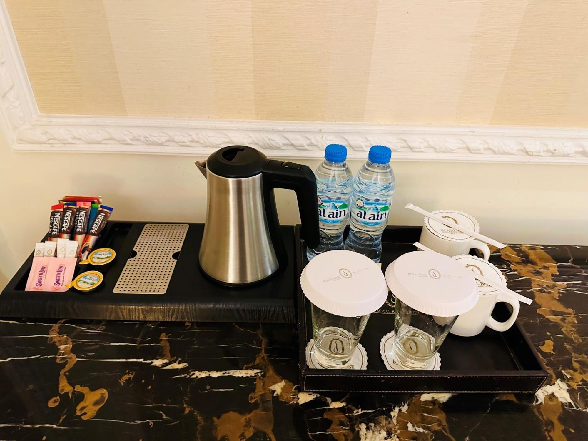 Royal Rose Abu Dhabi, A Curio Collection By Hilton Affiliated Hotel Exterior photo The photo shows a beverage station set up on a polished surface. It includes a stainless steel kettle, a tray with various condiments, and two cups. There are also two bottles of water positioned next to the kettle. The condiments consist of sugar pa