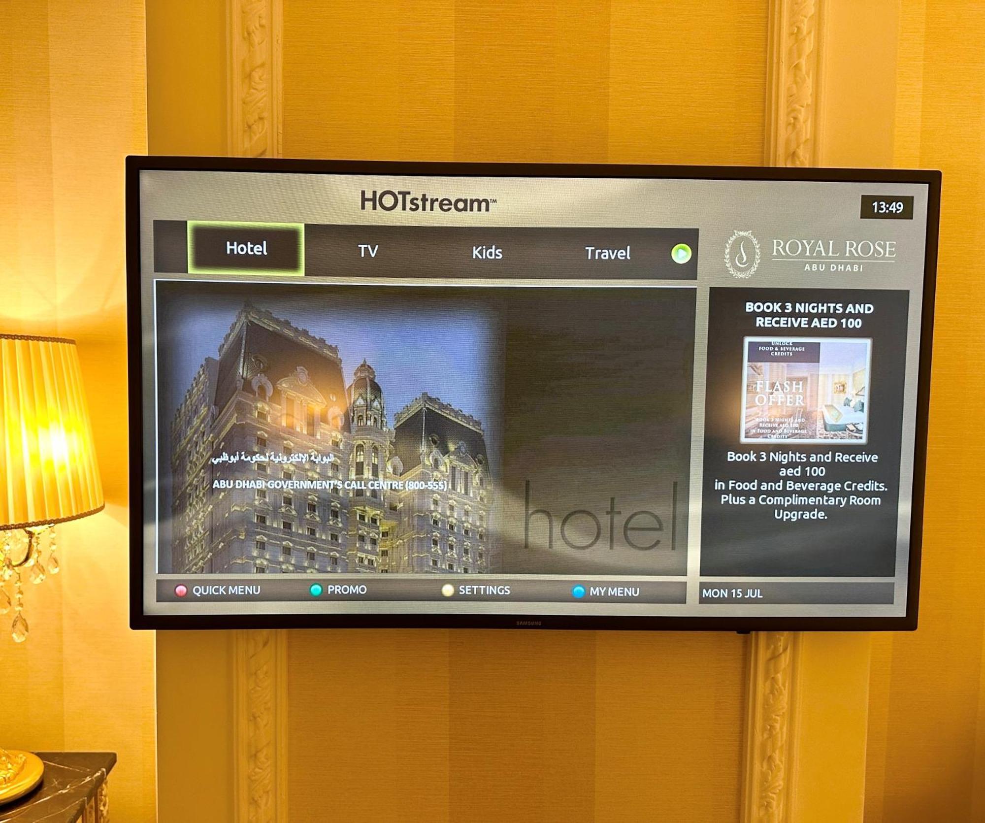 Royal Rose Abu Dhabi, A Curio Collection By Hilton Affiliated Hotel Exterior photo The photo shows a television displaying a hotel information interface labeled "HOTStream." The screen features several options, including "Hotel," "TV," "Kids," and "Travel." There is a prominent advertisement for the "Royal Rose" hotel, promoting a 